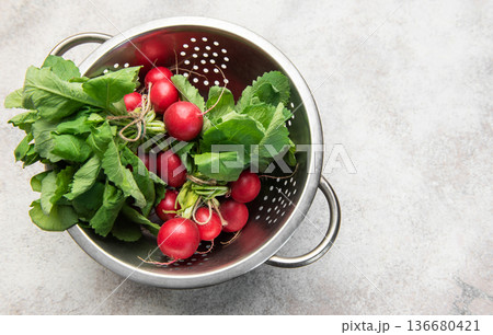 Fresh harvest radish with green leaves in colander Fresh harvest radish with green leaves in colander 136680421
