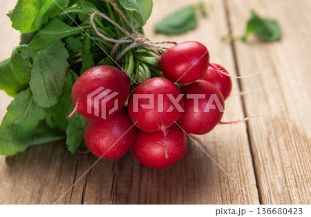 Fresh radishes bunch with green leaves on wood table Fresh radishes bunch with green leaves on wood table 136680423