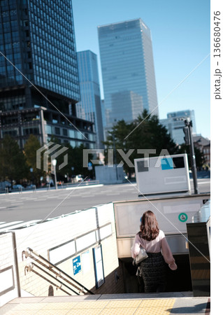 Asian businesswoman in a light pink blouse walking down the entrance of a Tokyo Metro subway station in the Marunouchi business district, Japan Asian businesswoman in a light pink blouse walking down the entrance of a Tokyo Metro subway station in the Marunouchi business district, Japan 136680476