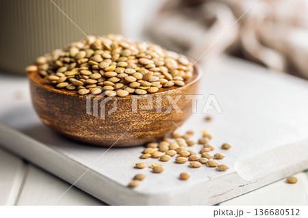 Uncooked green lentil in bowl on white table. Uncooked green lentil in bowl on white table. 136680512