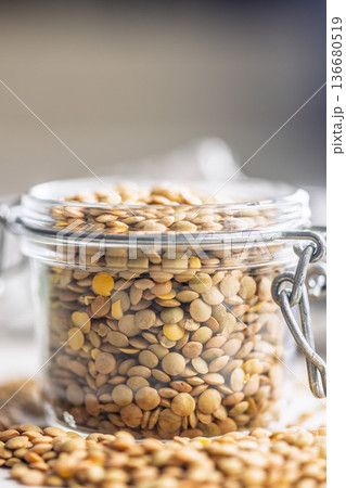 Uncooked green lentil in jar on white table. Uncooked green lentil in jar on white table. 136680519