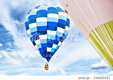Colorful hot air balloon flying over blue sky with white clouds 136680931