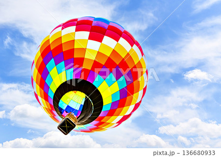 Colorful hot air balloon flying over blue sky with white clouds 136680933