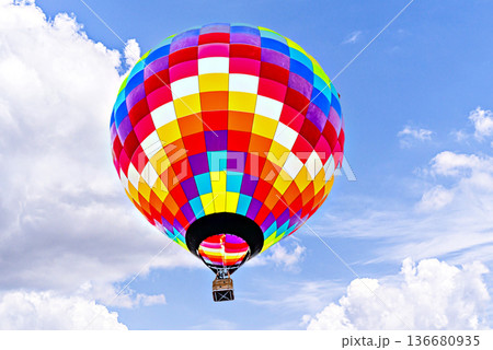 Colorful hot air balloon flying over blue sky with white clouds Colorful hot air balloon flying over blue sky with white clouds 136680935