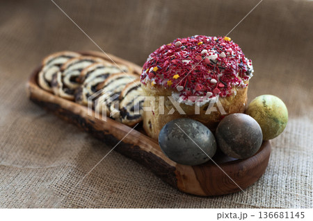 Top view of traditional Easter table with three dyed eggs, homemade glazed Easter bread and sliced poppy seed roll arranged on a long wooden serving board Top view of traditional Easter table with three dyed eggs, homemade glazed Easter bread and sliced poppy seed roll arranged on a long wooden serving board 136681145