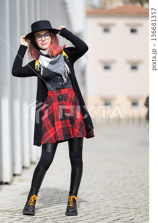 Young woman smiling in plaid skirt and hat 136681357