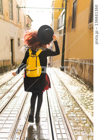 Woman with backpack exploring old city tram tracks Woman with backpack exploring old city tram tracks 136681360