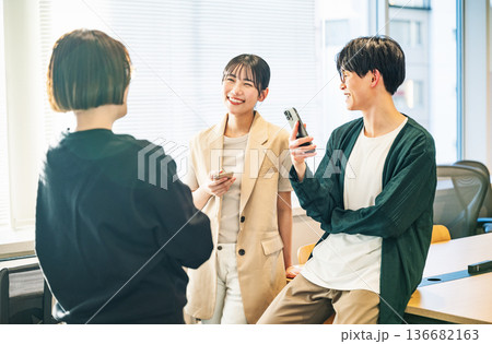 スマホを持ちながら談笑をする若い男女 136682163