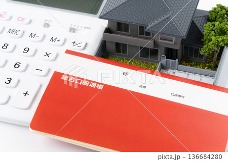 電卓と預金通帳とミニチュアの一戸建て住宅 電卓と預金通帳とミニチュアの一戸建て住宅 136684280