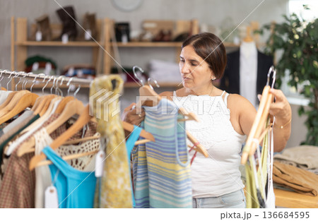 Latin woman customer turn over and choose something summer cloth in store, 136684595