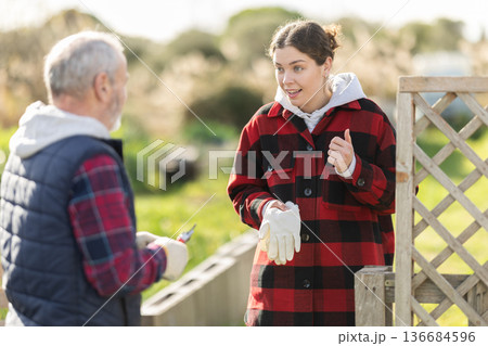 Young woman and elderly man talking in garden 136684596