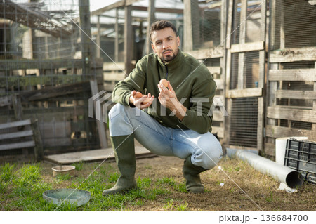 Positive man stands and holds in hands palms few fresh chicken eggs Positive man stands and holds in hands palms few fresh chicken eggs 136684700