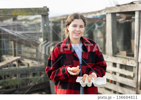 Positive girl stands and holds in hands palms few fresh chicken eggs Positive girl stands and holds in hands palms few fresh chicken eggs 136684811