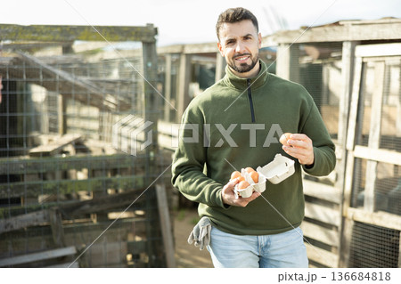 Positive man stands and holds in hands palms few fresh chicken eggs Positive man stands and holds in hands palms few fresh chicken eggs 136684818