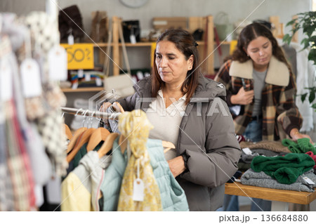 Selective Latina woman choosing something for autumn-winter in clothing store 136684880