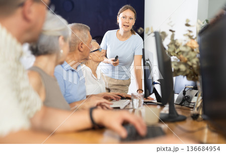 Woman teacher teaching elderly people how to use computer Woman teacher teaching elderly people how to use computer 136684954