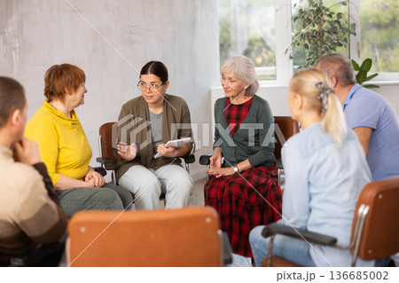 Young female tutor communicating with elderly people in language club Young female tutor communicating with elderly people in language club 136685002