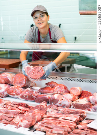 Young woman seller lays out beef in butcher shop Young woman seller lays out beef in butcher shop 136685087