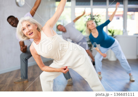 Active mature men and women practicing Jazz-funk dance in training hall Active mature men and women practicing Jazz-funk dance in training hall 136685111