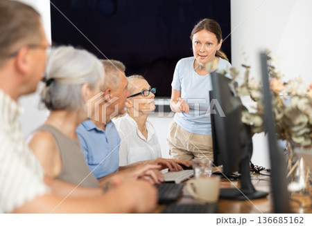 Woman teacher teaching elderly people how to use computer Woman teacher teaching elderly people how to use computer 136685162