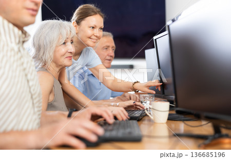 Female teacher helps an elderly woman learn how to use computer in nursing home Female teacher helps an elderly woman learn how to use computer in nursing home 136685196