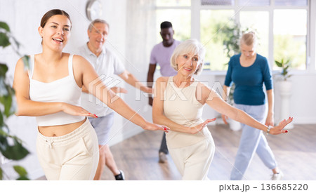 Men and women of different ages practicing Hip-hop dance in training hall 136685220