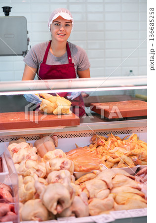 Young woman seller lays out chicken in butcher shop Young woman seller lays out chicken in butcher shop 136685258