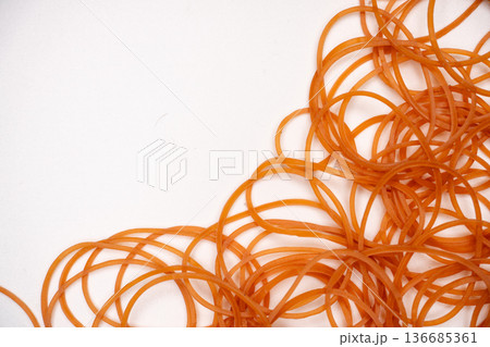 オレンジ色の輪ゴムが重なる背景素材 136685361