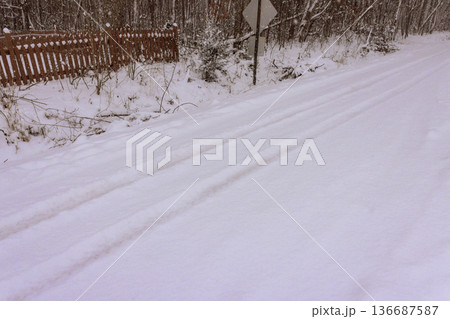 Snow covers quiet road in forest area during winter time in early morning hours Snow covers quiet road in forest area during winter time in early morning hours 136687587