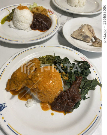 Nasi Padang, a traditional Indonesian dish from West Sumatra, featuring steamed rice served with a variety of rich, flavorful side dishes like rendang, sambal, and gulai. A hearty and iconic meal! Nasi Padang, a traditional Indonesian dish from West Sumatra, featuring steamed rice served with a variety of rich, flavorful side dishes like rendang, sambal, and gulai. A hearty and iconic meal! 136688086