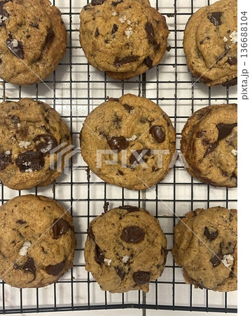 Freshly baked cookies with a golden-brown finish and chocolate chips. Perfectly crisp on the edges with a soft center, offering a delicious, comforting treat for any occasion. 136688104