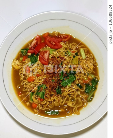 Indomie goreng, a popular Indonesian instant noodle dish, stir-fried to perfection with a blend of savory seasonings. Often served with fried egg, crispy shallots, and vegetables for flavor Indomie goreng, a popular Indonesian instant noodle dish, stir-fried to perfection with a blend of savory seasonings. Often served with fried egg, crispy shallots, and vegetables for flavor 136688324