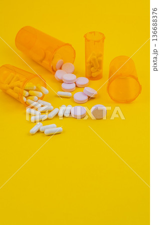 Pills and containers scattered on yellow background Pills and containers scattered on yellow background 136688376