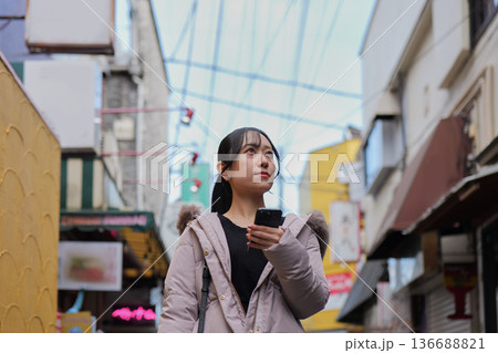 東京のレトロな商店街をスマートフォンを見ながら散策する笑顔の若い女性 東京のレトロな商店街をスマートフォンを見ながら散策する笑顔の若い女性 136688821