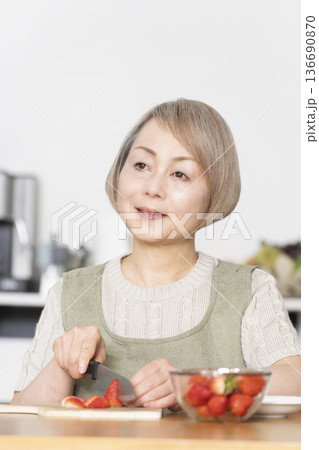 ダイニングキッチンでいちごを切りヨーグルトのデザートを作り食べる 136690870