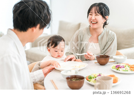 食卓で赤ちゃんに離乳食,ご飯を食べさせる母親と父親（育児・子育て） 136691268