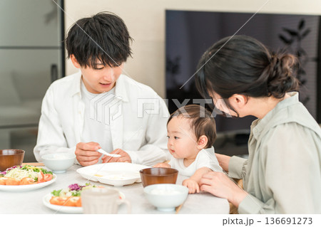 食卓で赤ちゃんに離乳食,ご飯を食べさせる母親と父親（育児・子育て） 136691273
