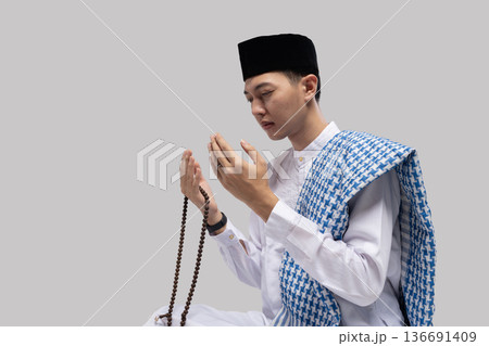 Focused man with rosary beads. Detailed image of man gripping rosary with thoughtful expression Focused man with rosary beads. Detailed image of man gripping rosary with thoughtful expression 136691409
