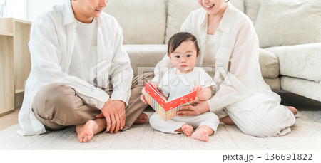 マイホームのリビングで子供,赤ちゃんに絵本を読む子育て世代のファミリー（育児,子育て,スキンシップ） 136691822