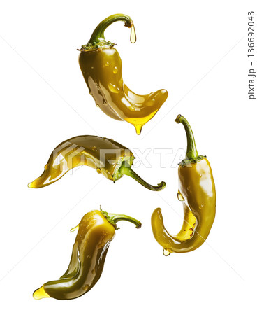 Shiny green chili peppers covered in oil, isolated on white background, emphasizing food freshness and culinary splash concept 136692043