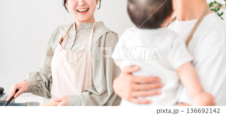 キッチンで赤ちゃんを抱っこするエプロン姿の夫婦,ファミリー 136692142