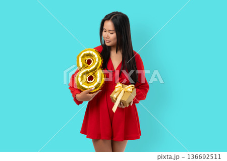 A young woman holds a number 8 balloon and a gift 136692511