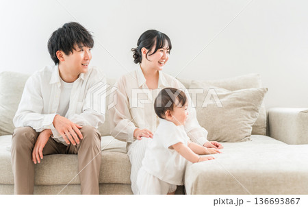 マイホームのリビングソファーで赤ちゃんと過ごす若いファミリー,家族 136693867