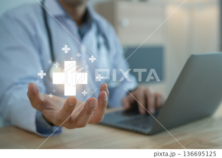 Doctor holding glowing medical cross icon over palm with laptop, Healthcare service and insurance concept Doctor holding glowing medical cross icon over palm with laptop, Healthcare service and insurance concept 136695125