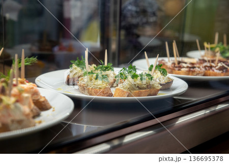 しらすを乗せたピンチョスやブルスケッタなどのバル料理 ビストロのショーケースに並ぶお洒落な前菜や軽食 しらすを乗せたピンチョスやブルスケッタなどのバル料理 ビストロのショーケースに並ぶお洒落な前菜や軽食 136695378