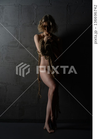Shibari scene with naked woman in low light setting at indoor location 136696742