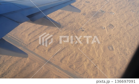 Aerial view of desert landscape with airplane wing and road visible 136697091