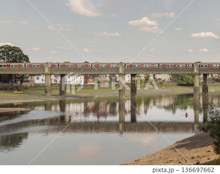 A testament to Victorian engineering, the Strand-on-the-Green Bridge arches across the Thames with quiet dignity. The intricate lattice of its five wrought-iron spans creates a delicate metallic lace 136697662
