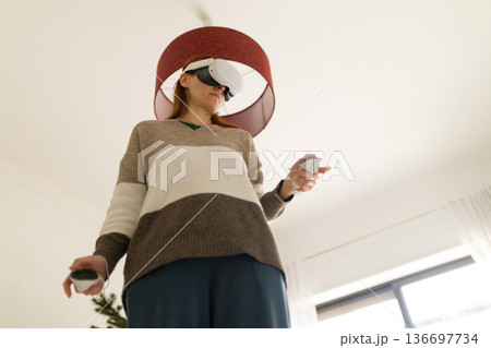 Woman experiencing metaverse with vr headset and controllers 136697734