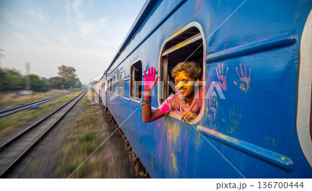 Happy Young Man Covered in Holi Powder Waving from Moving Blue Train Window 136700444